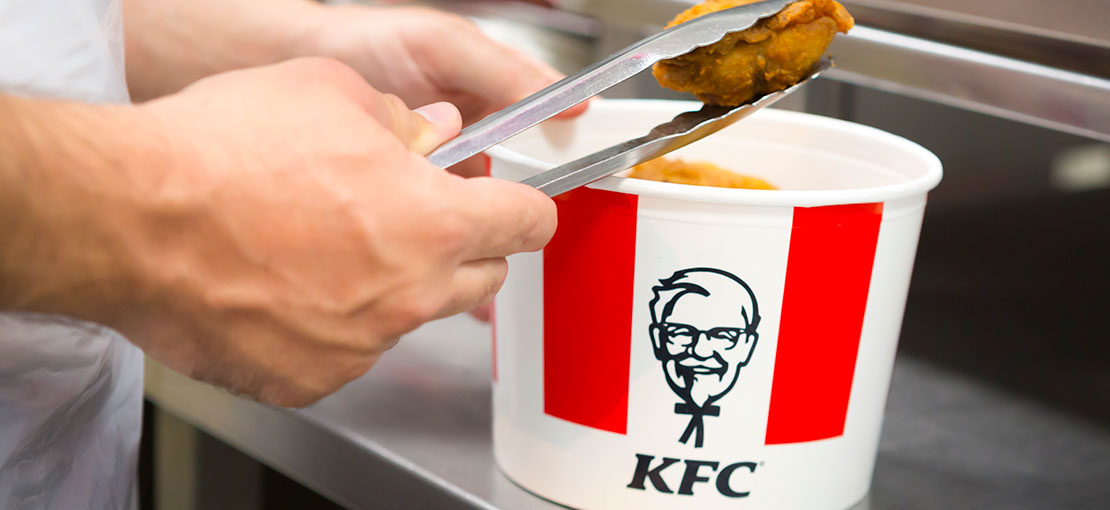 Un addetto riempie un contenitore di pollo fritto KFC.