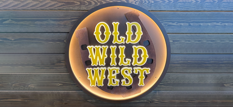Insegna del locale Old Wild West, con scritta al led giallo su parete in legno